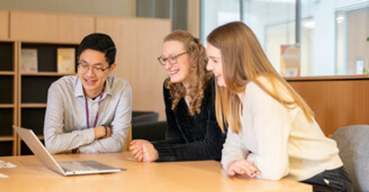 3 students at a table with a laptop
