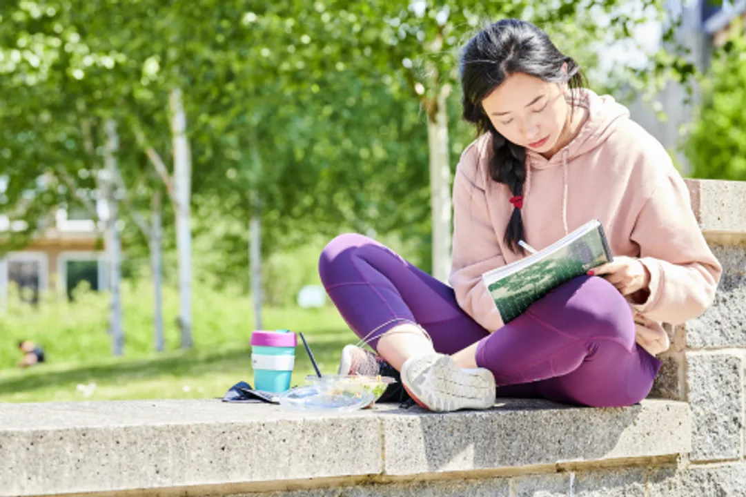 Young woman sitting on a wall  reading