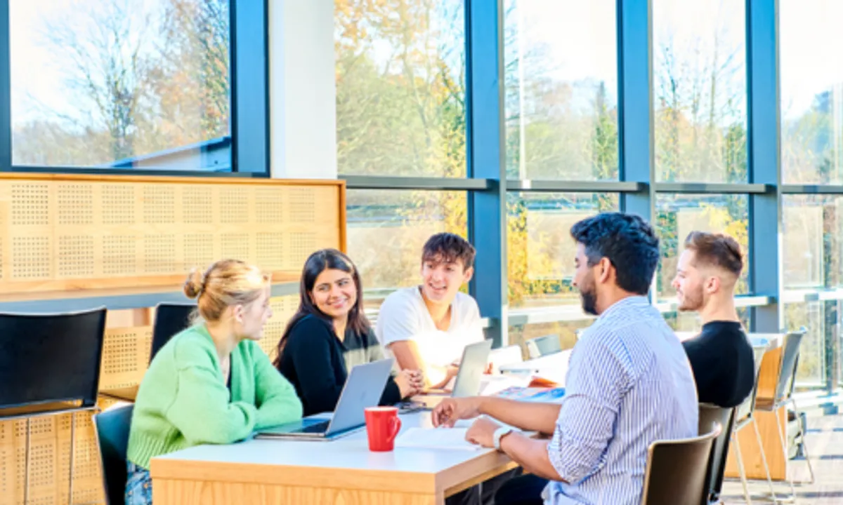 Group of students chatting with laptops at a table