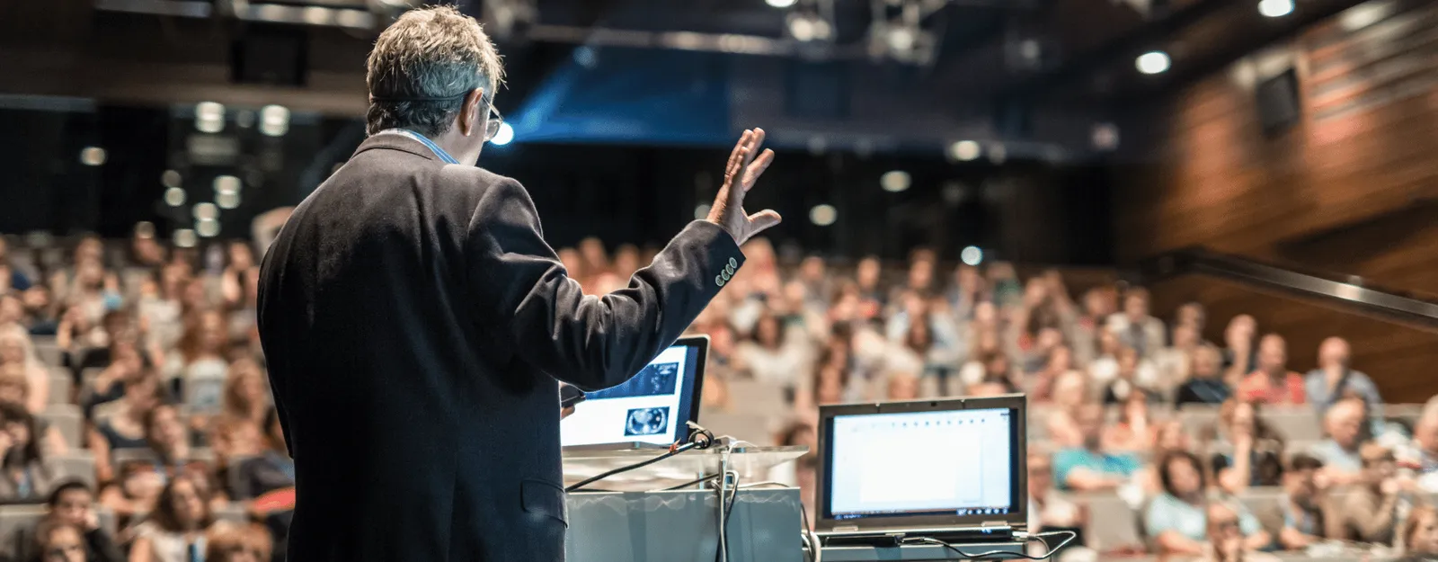Man talking at a conference from behind addressing the crowd
