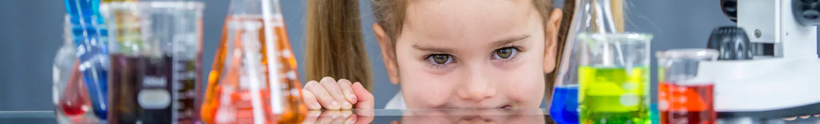 Child smiling surrounded by test tubes and other science equipment