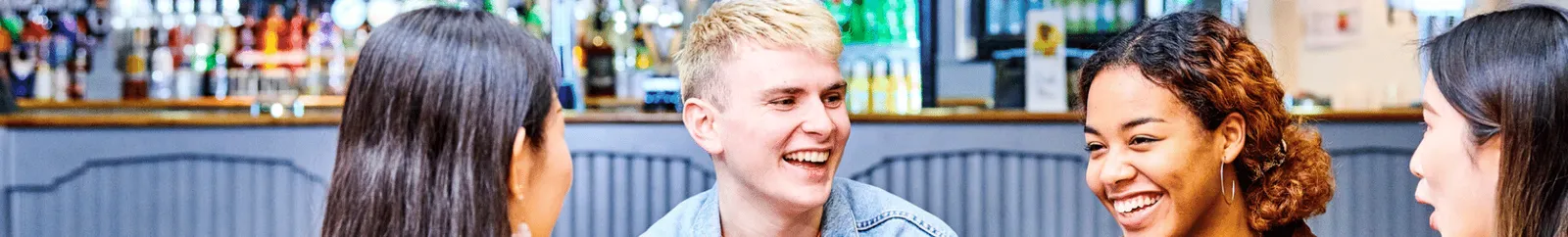 Four students laughing in a college bar