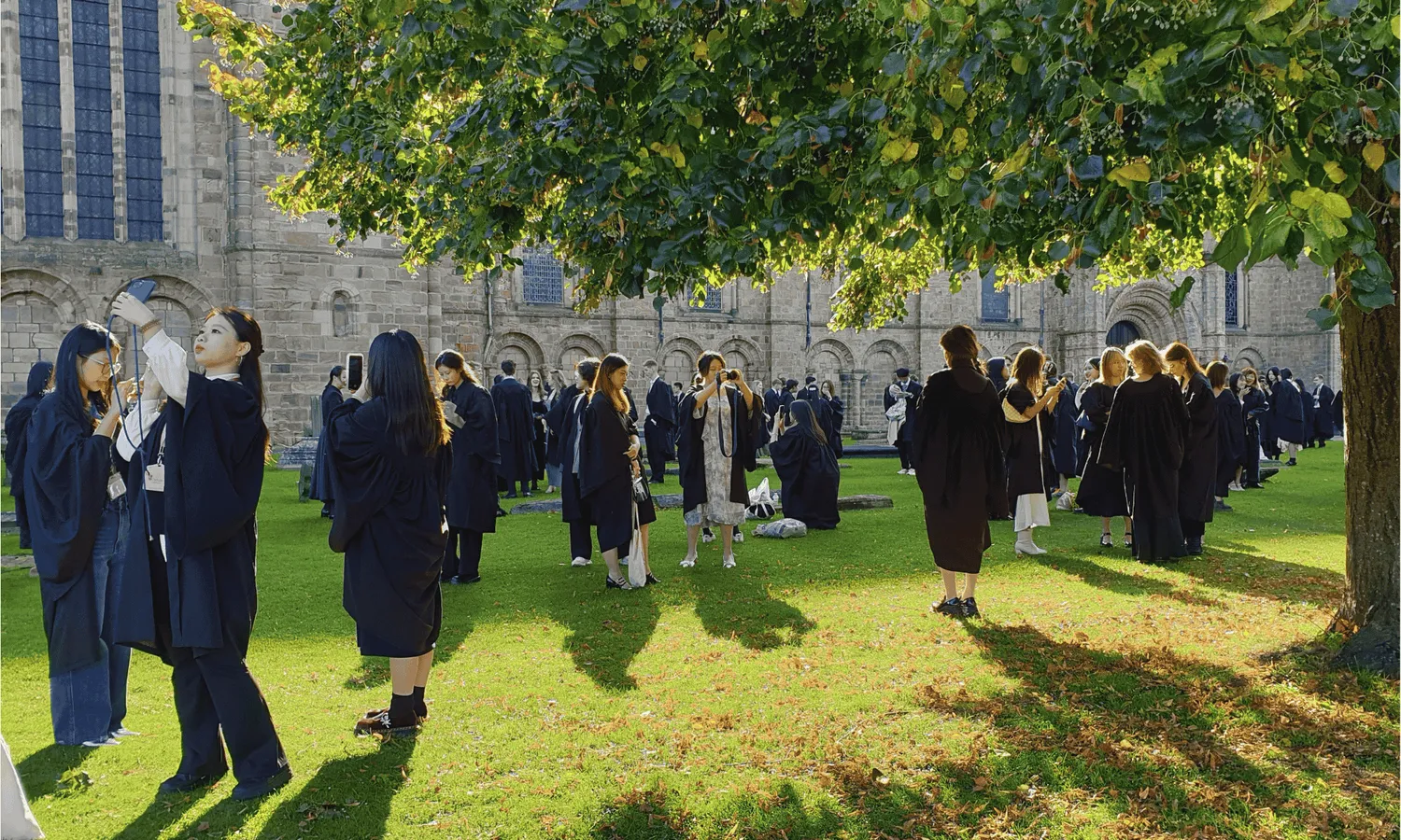 Students in robes on the grass outside Durham Cathedral