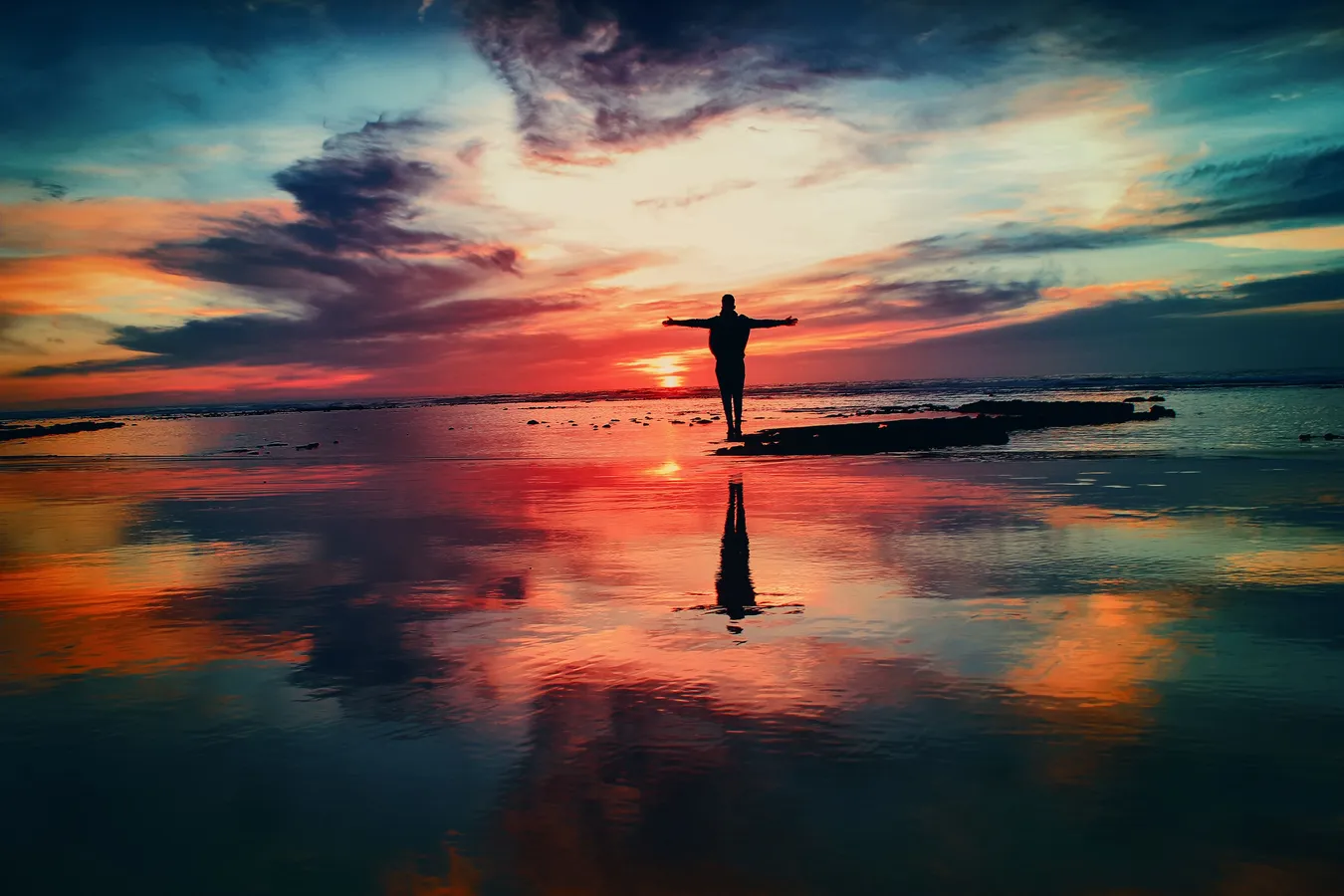 Silhouette of a person looking out to sea during a sunset