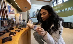 A person looks at an item in the Durham World Heritgae Site Visitor Centre Shop