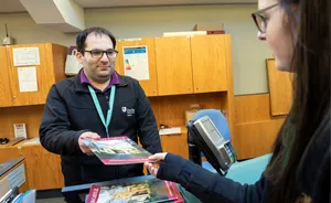 A visitor buys a book from the front desk at Palace green