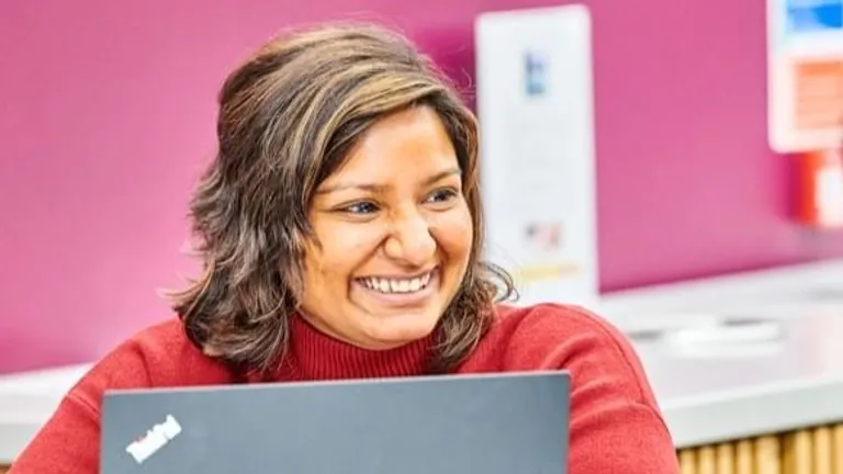A mature female student smiling while working on a laptop