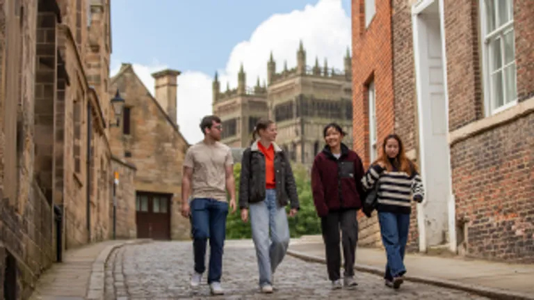 A group of four students walks down the hill in front of the cathedral