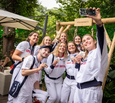 The womens eight+ rowing team taking a selfie together with their bronze medals