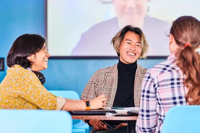 Students chatting in front of a screen