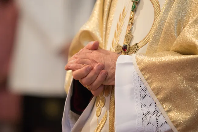 Catholic priest holding praying hands