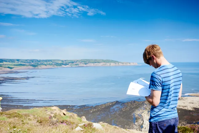 Man reading while overlooking sea