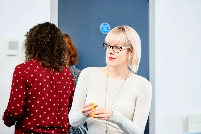 Woman with blonde hair listening to conversations around her