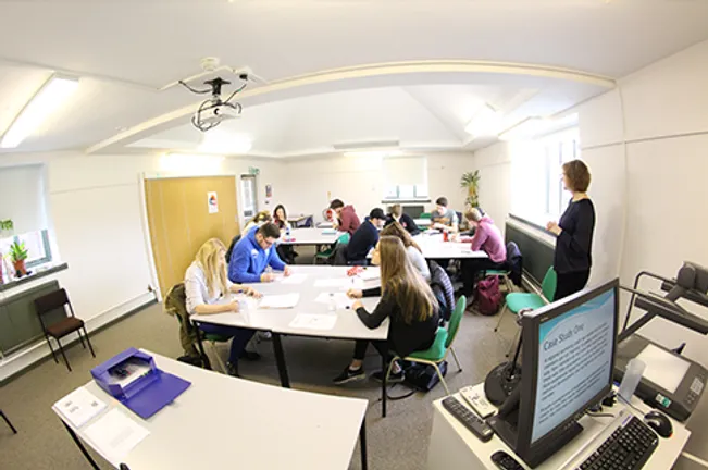 Students working around tables as a lecturer looks on