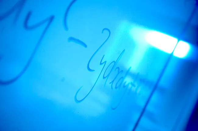 A mathematical equation on a wipe board