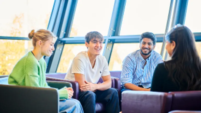 A mixed group of students sat in comfy chairs chatting