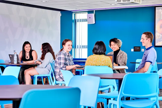 Students socialising at tables in South College social space
