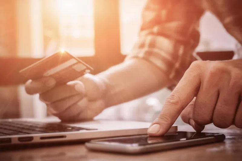 Man hands with a credit card, calculator and laptop.