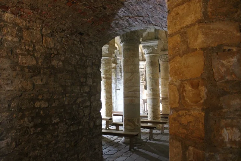 Photograph looking in to the Norman Chapel and Durham Castle, showing several illuminated stone columns beside thick stone walls