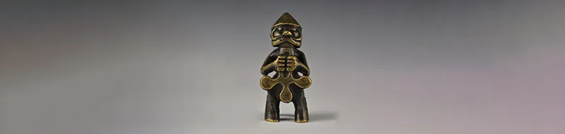 Photograph of a replica of a Viking-era bronze statue of Thor holding a hammer while sat on a throne and wearing a conical hat or helmet.