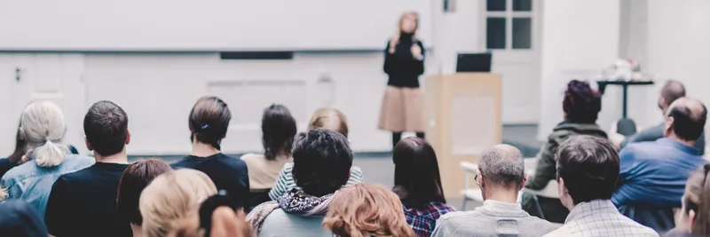 Female speaker giving presentation on business conference banner 1050x350px
