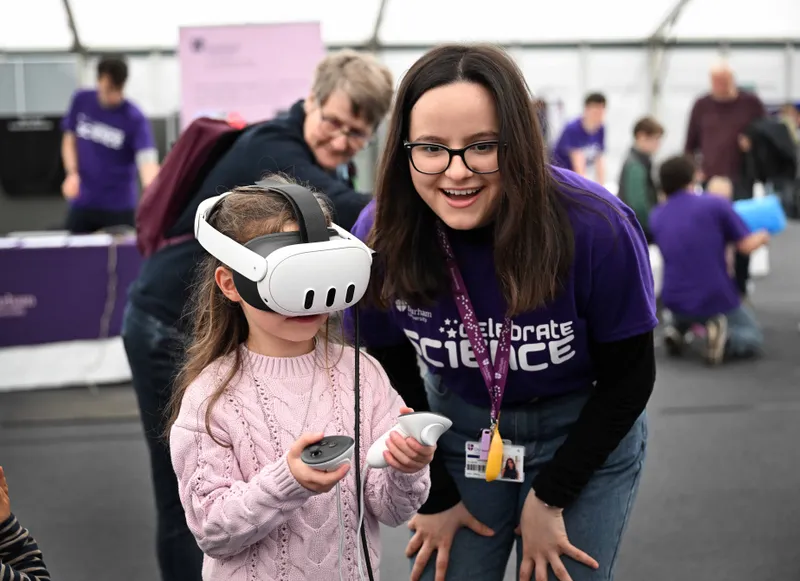 A Celebrate Science volunteer helps a child with a VR headset.
