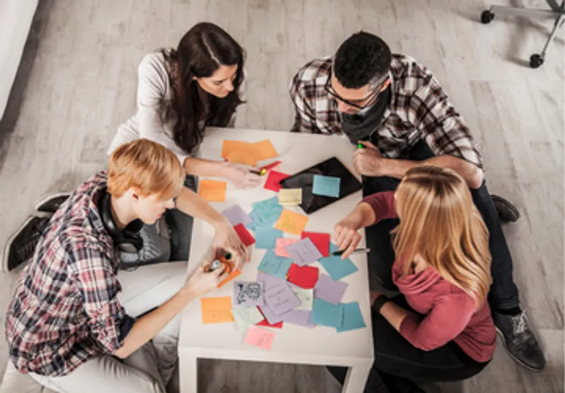 people gathered around a table full of post-it notes