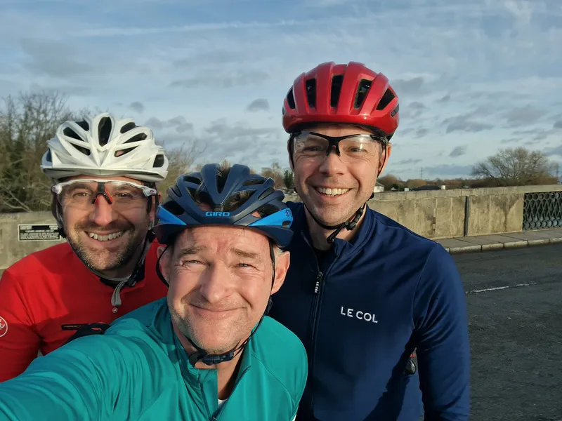 Three men wearing cyling gear smiling at the camera