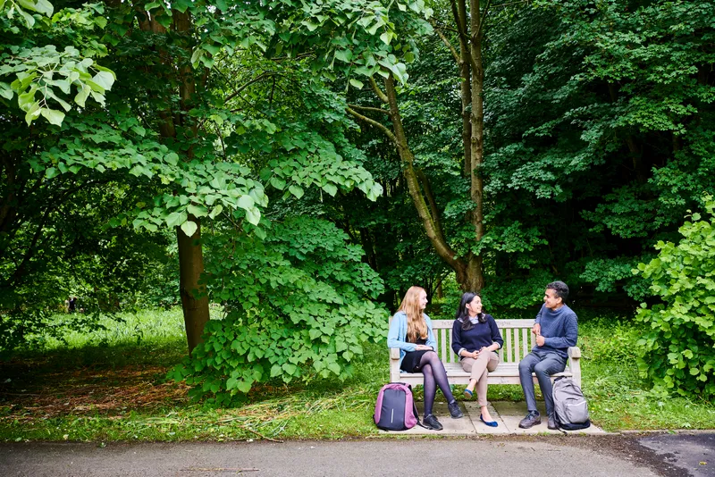 Students sitting on an outdoor bench in the gardens