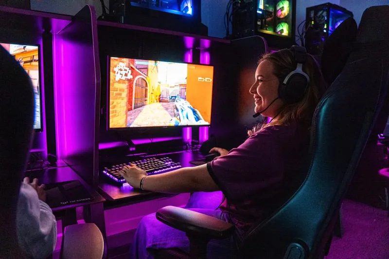 A smiling female gamer sitting in front of a computer game