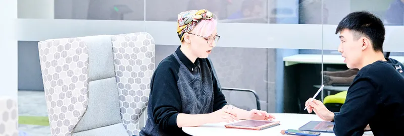 Two students sitting opposite each other on laptops