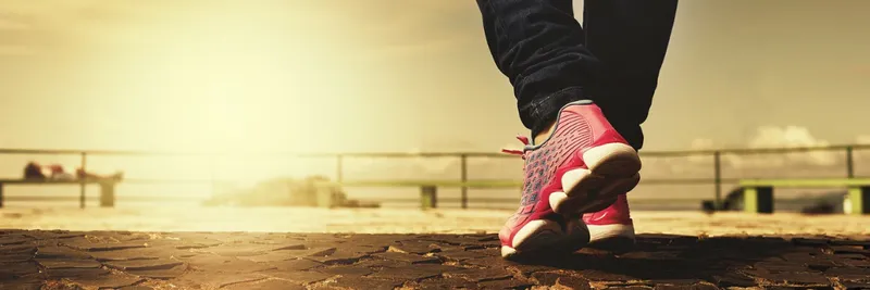 The feet of a person wearing bright trainings walking along a path