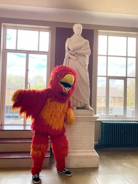 a person in a phoenix costume next to a statue of Charles. Earl Grey II