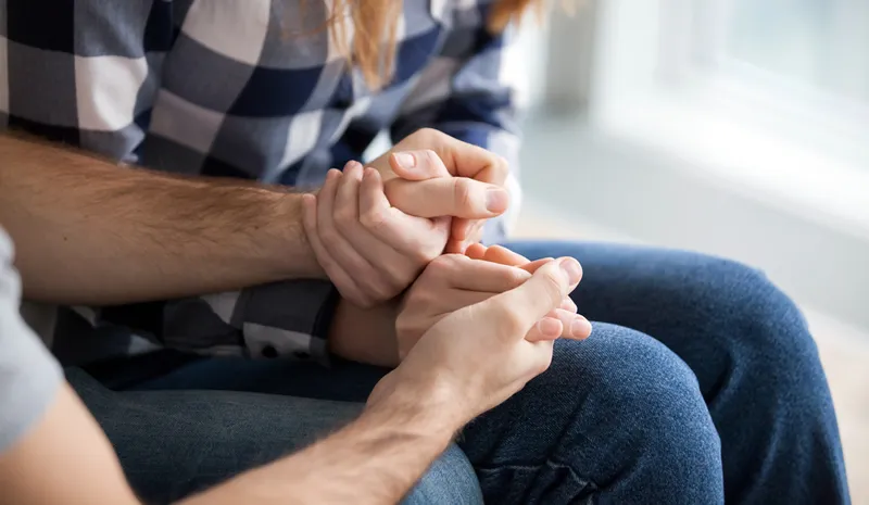People reassuringly holding hands with one another