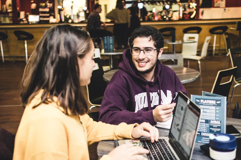 Two students working and chatting in the student bar and cafe