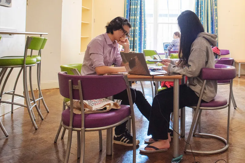 Students sat at a table with laptops