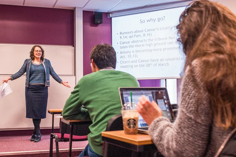 Students on a laptop listening to lecturer.