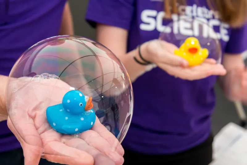 Celebrate Science festival volunteers holding rubber ducks in bubbles