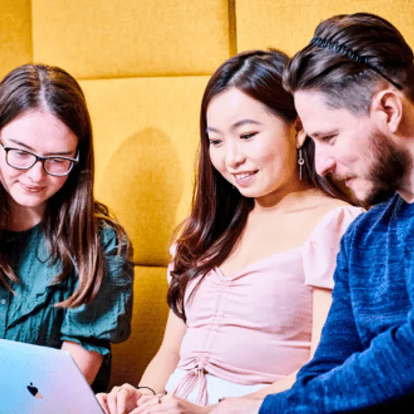 Three students looking at a laptop