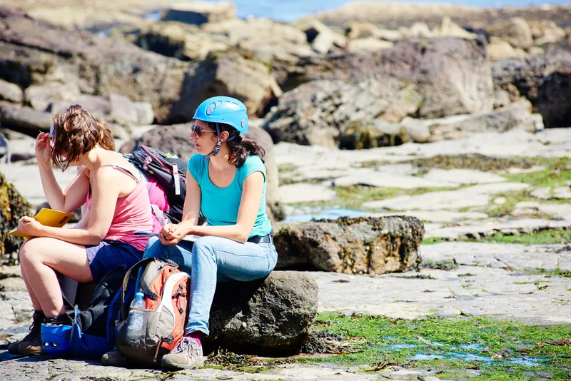 Woman sat on rocks wearing helmet