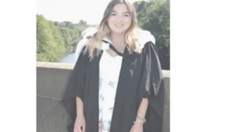 A picture of a student wearing a black and white graduation gown.