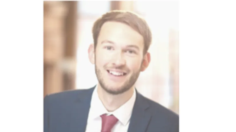 Image of a male graduate wearing a suit and a red tie.