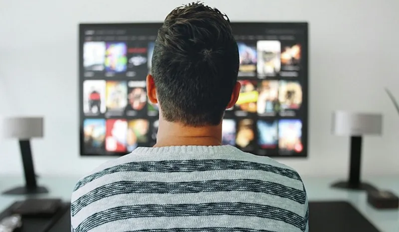 Male figure facing away from camera whilst looking at a tv screen