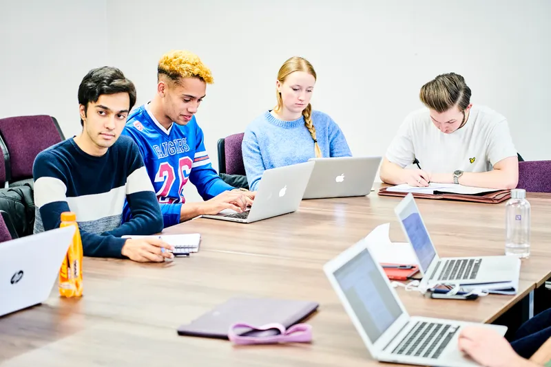Students sitting round a table with laptops