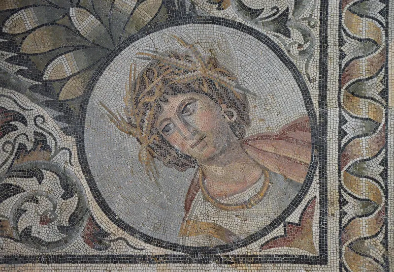 Mosaic depicting an image of a human's face with a crown of leaves