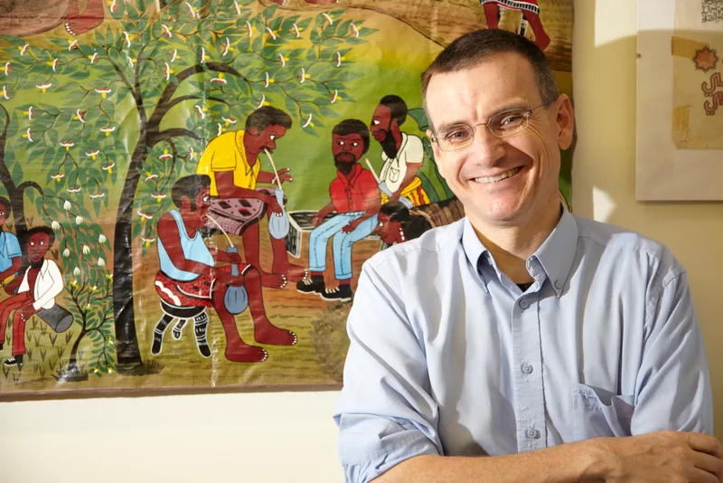 Headshot of a professor in front of aboriginal artwork