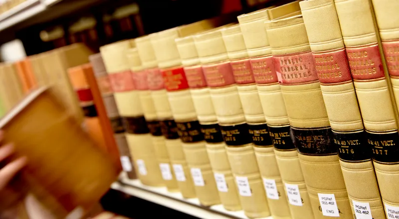 Close-up of hand pulling law book off shelf