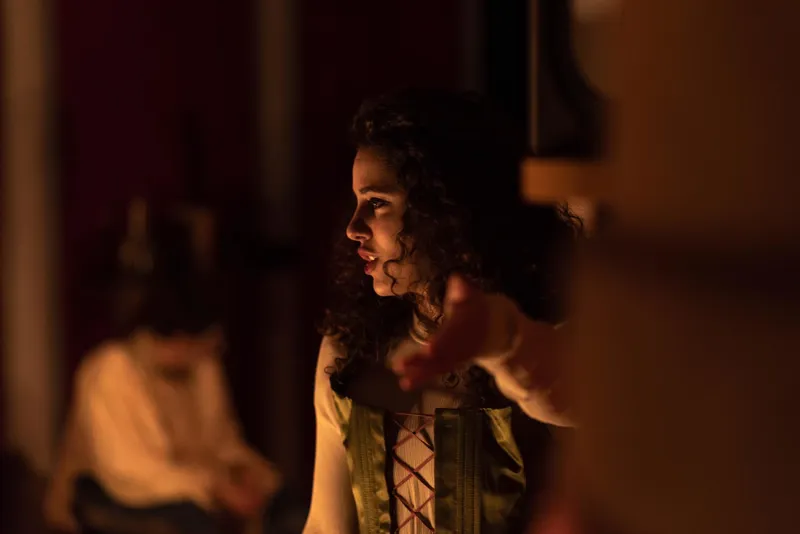 A woman in dramatic stage lighting gesturing