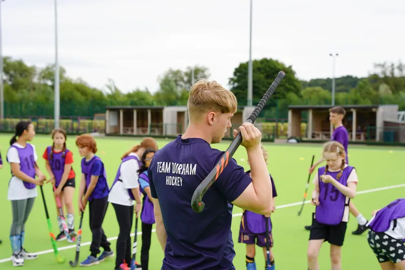 Student Jack with hocky stick over his shoulder facing away from camera