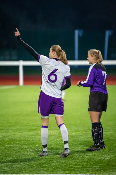 Two football players standing at the side of a pitch during a match